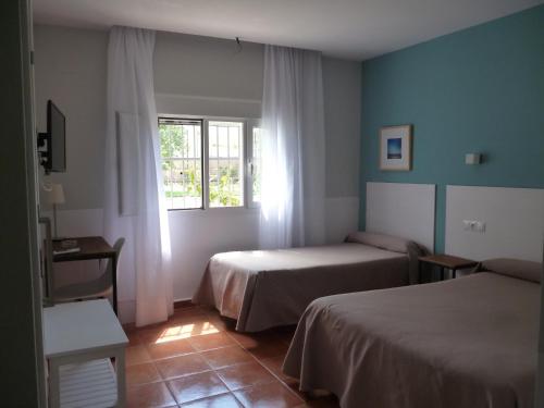 a hotel room with two beds and a window at Hostal Las Cumbres in Conil de la Frontera