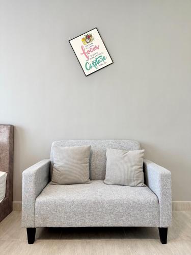 a couch in a living room with a clock on the wall at Sunsuria Forum SOHO & Residence Suites Setia Alam by MOKA in Shah Alam