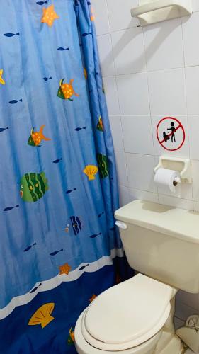 a bathroom with a toilet and a blue shower curtain at Hostal El Mirador in Minca
