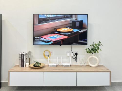 a tv hanging on a wall above a white dresser at Sunsuria Forum SOHO & Residence Suites Setia Alam by MOKA in Shah Alam