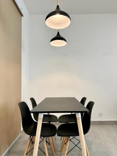 a black dining table with black chairs and a light fixture at Sunsuria Forum SOHO & Residence Suites Setia Alam by MOKA in Shah Alam