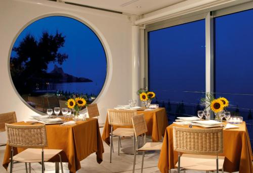 a dining room with tables and chairs and large windows at Hotel Amyclae in Sperlonga
