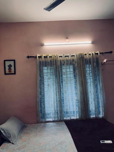 a bedroom with a bed and a window with curtains at Hello entire villa varkala cliff in Varkala
