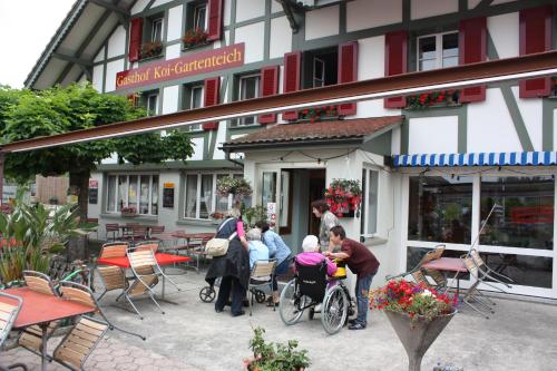 a group of people sitting outside of a building at Hotel Restaurant Koi-Gartenteich in Hausernmoos