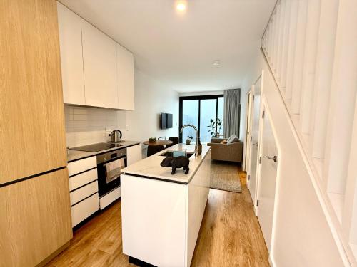 a kitchen with white cabinets and a kitchen island at Stylish 2 bedrooms townhouse in central Wellington with a free car park in Wellington