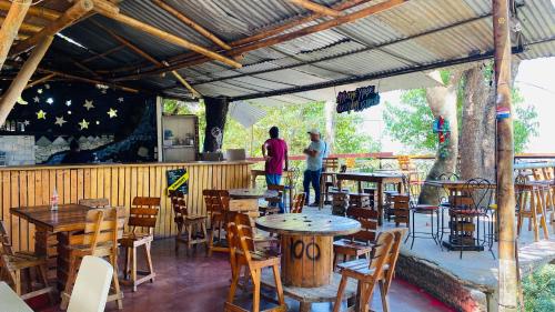two people standing in a restaurant with tables and chairs at Hostal El Mirador in Minca