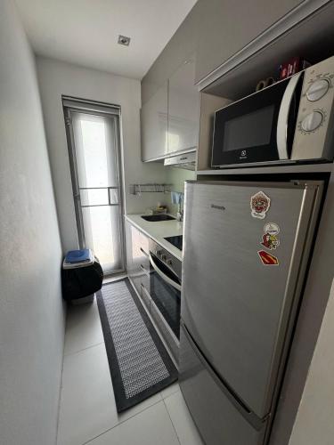 a small kitchen with a refrigerator and a microwave at Bangrak Cozy Stay in Koh Samui 