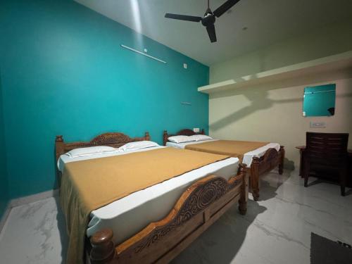 two beds in a room with a blue wall at Sri Arunachala Homestay in Tiruvannāmalai