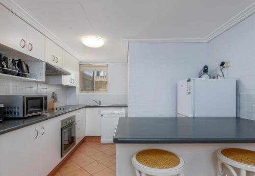 a kitchen with white cabinets and a white refrigerator at Bargara Beach Bliss in Bargara