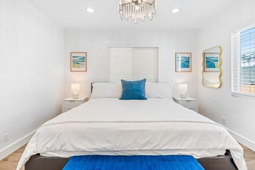 a white bedroom with a large bed with blue pillows at Maison on the Beach in Los Angeles