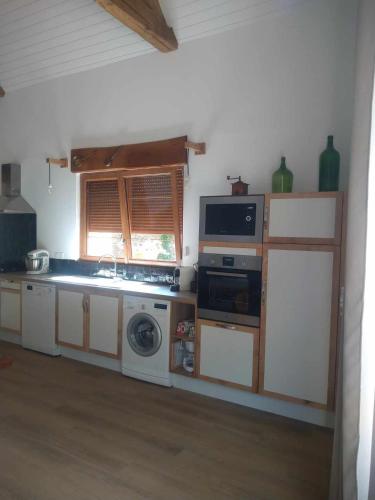 une cuisine avec une cuisinière et un micro-ondes dans l'établissement La Grange du Poussié, à La Salvetat-Peyralès