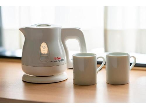 a tea kettle and two cups on a table at The OneFive Kyoto Shijo - Vacation STAY 41806v in Kyoto
