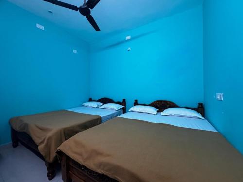 two beds in a room with a blue light at Sri Arunachala Homestay in Tiruvannāmalai