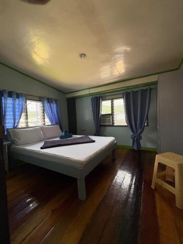 a large bed in a room with two windows at Color Hostel in Dapa