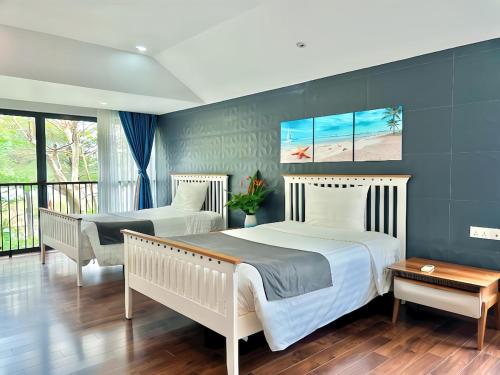 two beds in a bedroom with blue walls at Maribel Villa Phu Quoc in Phu Quoc