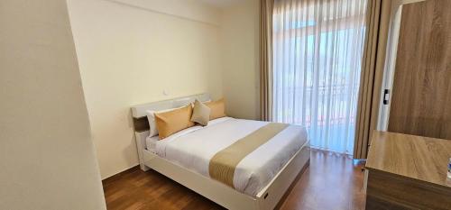 a white bedroom with a bed and a large window at Bole Central Apartment in Addis Ababa