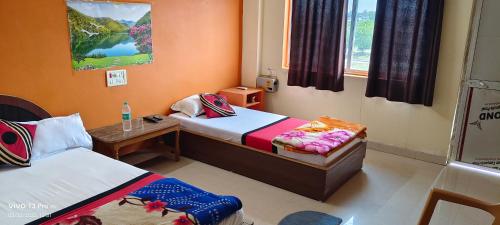 una piccola stanza con due letti e un tavolo di Mahima Guest House a Bodh Gaya