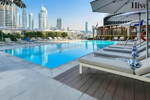 a swimming pool with chairs and an umbrella on a building at Luxury 2 Bed in Address Opera Residences in Dubai