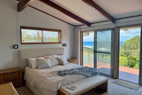 a bedroom with a bed and a large window at Everlong Mollymook in Mollymook