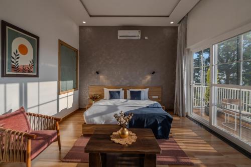 a bedroom with a bed and a couch and a table at SaffronStays The Rajpur in Rājpur