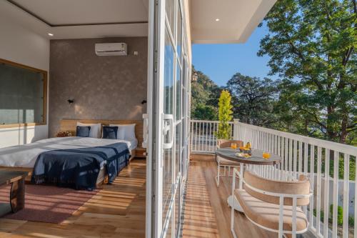 a bedroom with a bed and a balcony with a table at SaffronStays The Rajpur in Rājpur
