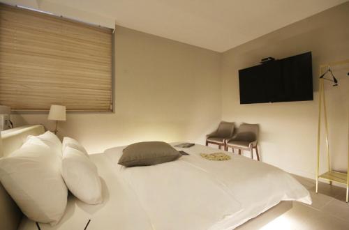 a bedroom with a white bed with a television on the wall at Hotel YAJA Gwangju Hanam branch in Gwangju