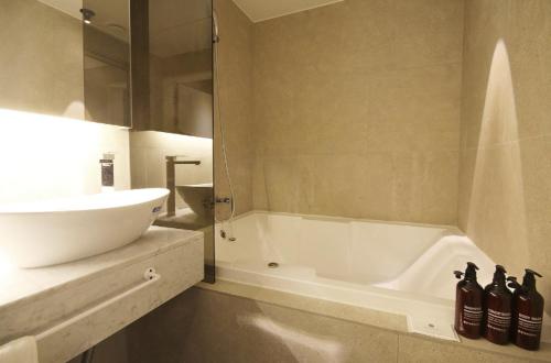 a bathroom with a white tub and a sink at Hotel YAJA Gwangju Hanam branch in Gwangju