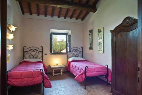 two beds in a room with pink sheets at Agriturismo Podere Campaini in Volterra