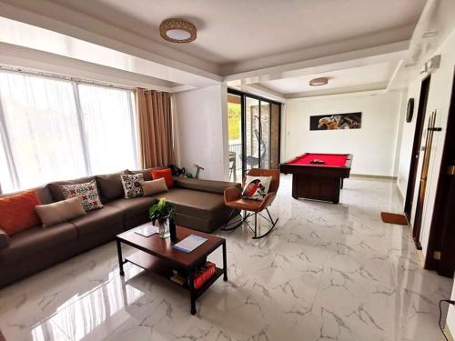 a living room with a couch and a pool table at Overlooking & Serene Resthouse wt Pool in Antipolo in Antipolo