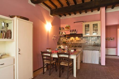 a kitchen with pink walls and a table and chairs at Agriturismo Podere Campaini in Volterra