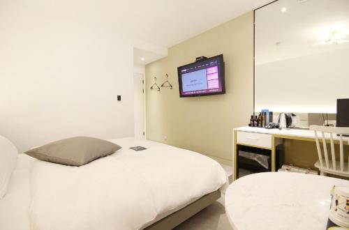 a bedroom with a bed and a desk and a tv at Hotel YAJA Gwangju Hanam branch in Gwangju
