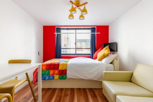a bedroom with red walls and a bed and a chair at jtr浅草橋401 in Tokyo