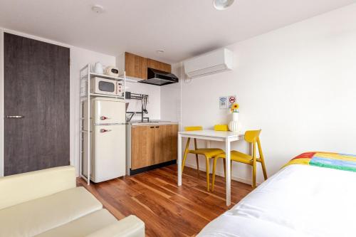a small apartment with a kitchen and a table with yellow chairs at jtr浅草橋401 in Tokyo