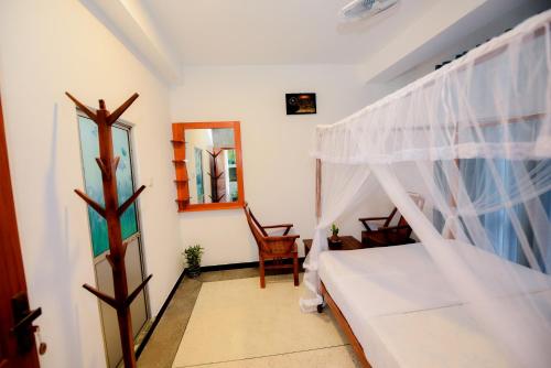 a bedroom with a bed and a window and a chair at Camellia Unawatuna in Unawatuna