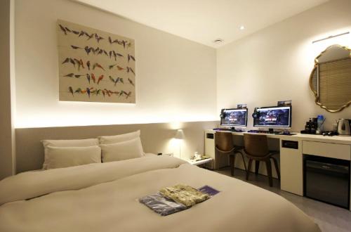 a hotel room with a bed and a desk with two monitors at Hotel YAJA Gwangju Hanam branch in Gwangju