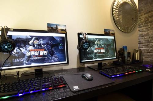a desk with two monitors and a keyboard and a mouse at Hotel YAJA Gwangju Hanam branch in Gwangju