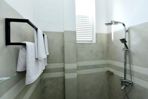 a bathroom with a shower with towels and a mirror at Camellia Unawatuna in Unawatuna