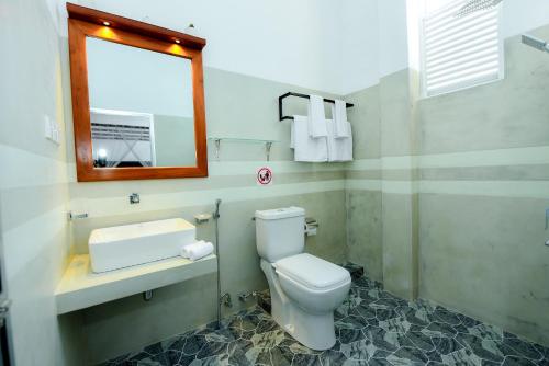 a bathroom with a toilet and a sink and a mirror at Camellia Unawatuna in Unawatuna