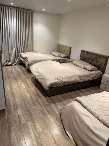 three beds in a room with wooden floors at شقة خمس غرف مطلة على طريق السودة in Abha
