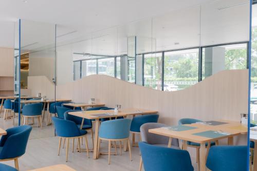 a restaurant with wooden tables and blue chairs at Wyndham Garden Naithon Phuket in Nai Thon Beach