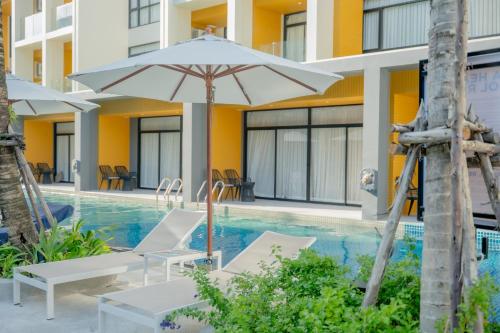 a swimming pool with chairs and an umbrella at Wyndham Garden Naithon Phuket in Nai Thon Beach