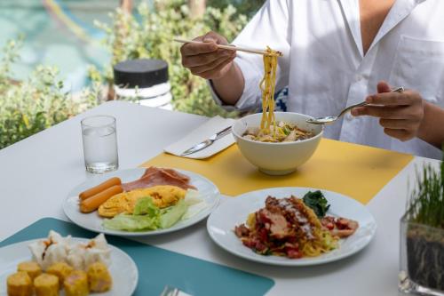 a person eating food on a table with plates of food at Wyndham Garden Naithon Phuket in Nai Thon Beach