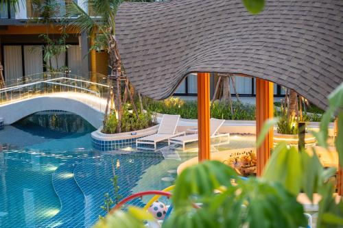 a swimming pool with two lounge chairs next to a building at Wyndham Garden Naithon Phuket in Nai Thon Beach