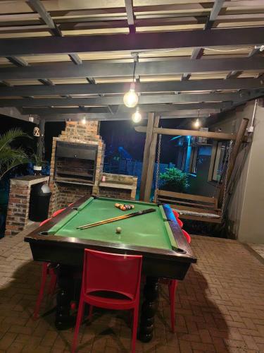 a pool table in a patio with two red chairs at Kudus Hide in Richards Bay