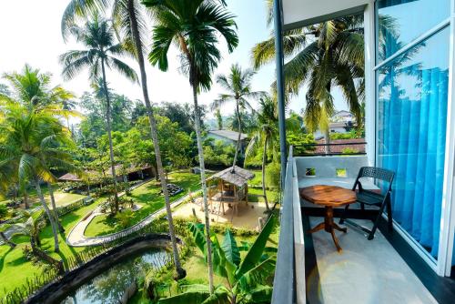 a balcony with a table and palm trees at Camellia Unawatuna in Unawatuna