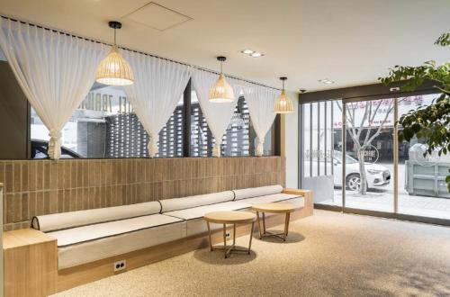 a living room with a couch and two tables and windows at Hotel 7 Bricks Gwangju Sangmu in Gwangju
