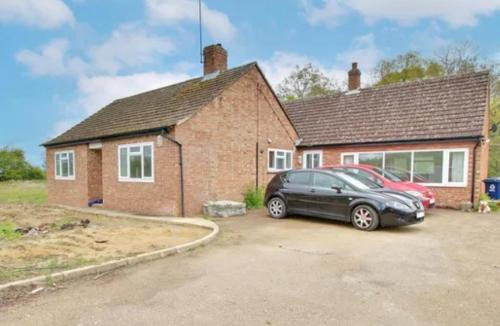 a house with two cars parked in a driveway at Staycation Bunglaw in Coppingford