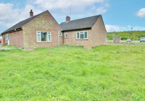 a brick house in a field with a green field at Staycation Bunglaw in Coppingford