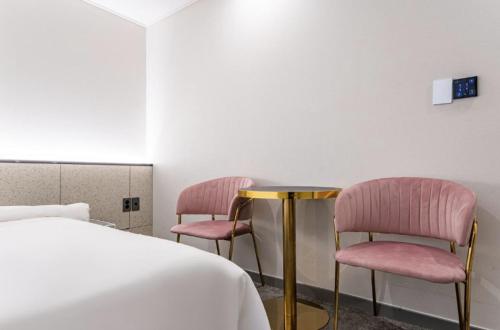 two pink chairs sitting next to a table in a room at Hotel 7 Bricks Gwangju Sangmu in Gwangju