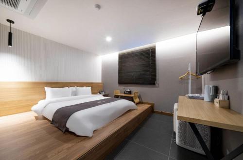 a bedroom with a large bed and a flat screen tv at Hotel 7 Bricks Gwangju Sangmu in Gwangju